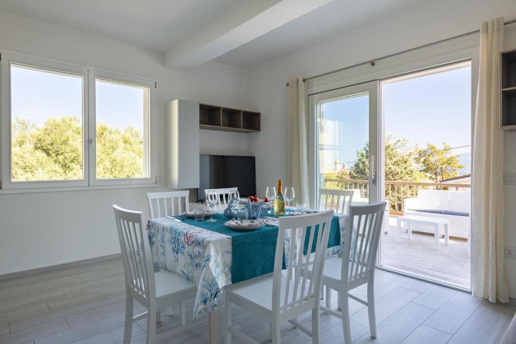 uma sala de jantar com mesa, cadeiras e janelas em Stella del mare em Cala Gonone