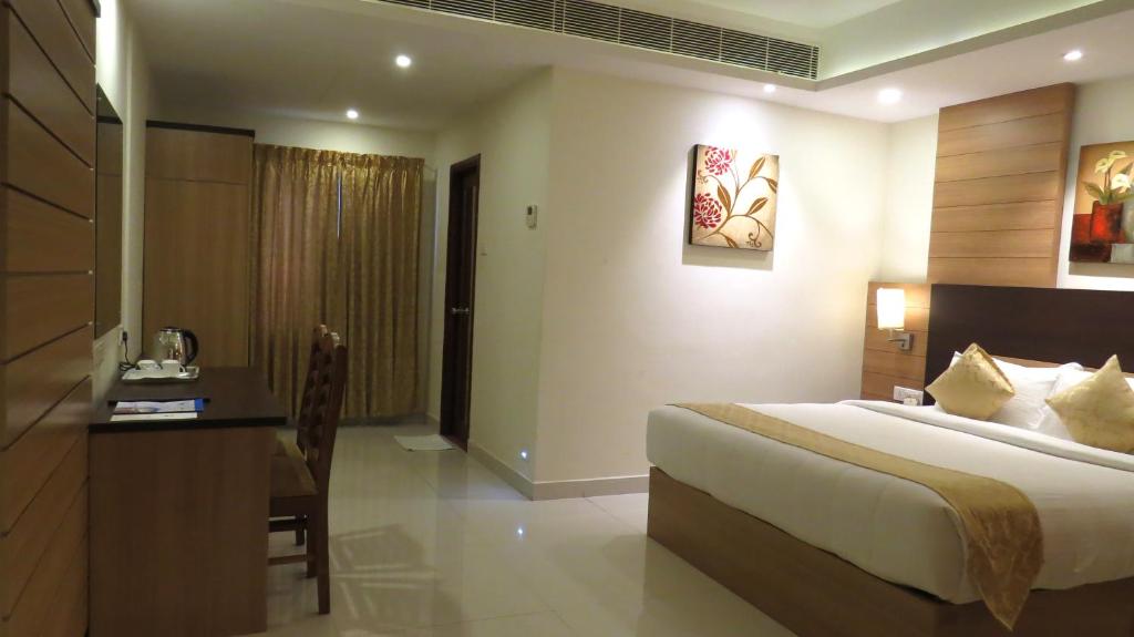 a bedroom with a bed and a desk in a room at Hotel Rajadhani in Trivandrum