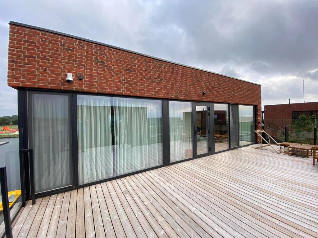 a building with sliding glass doors on a wooden deck at Apartamentai Svencele in Svenele