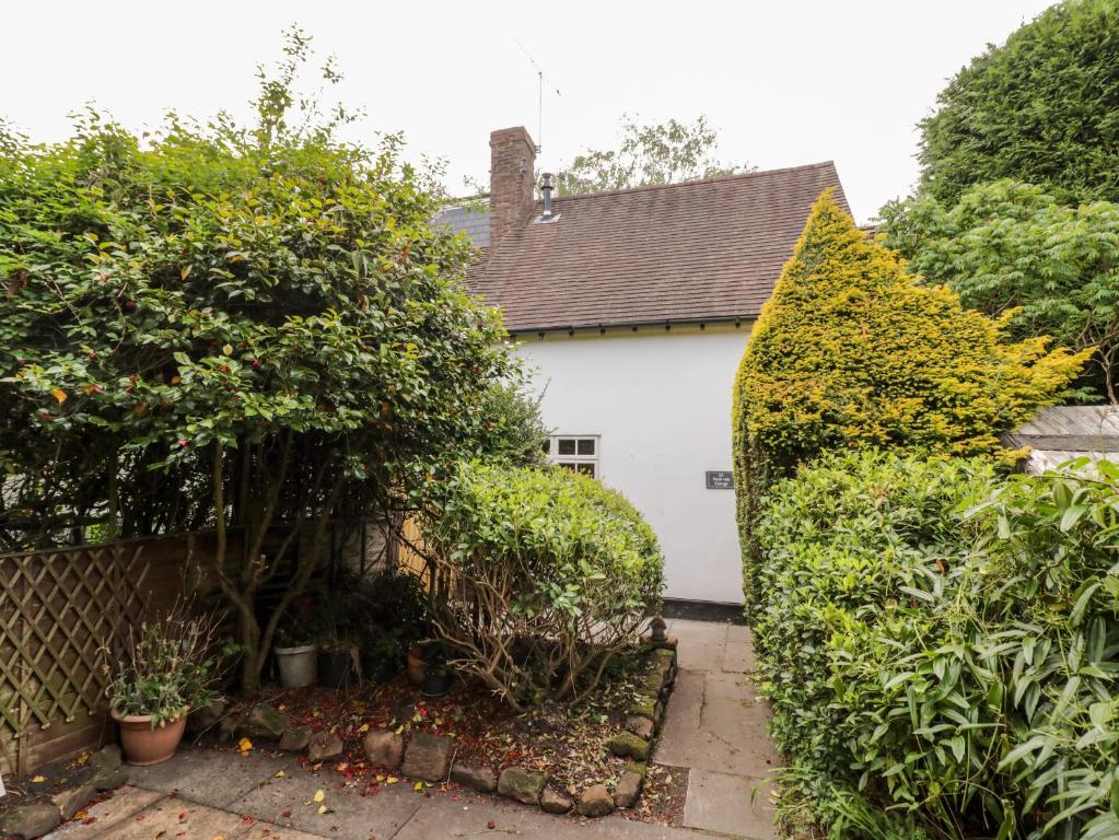 una casa blanca con arbustos y una valla en Hock-tide Cottage, en Kenilworth