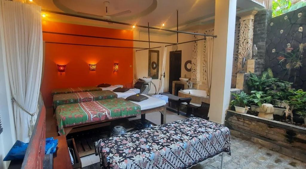 a bedroom with two beds and a desk and a sink at Rambutan Hotel in Lovina