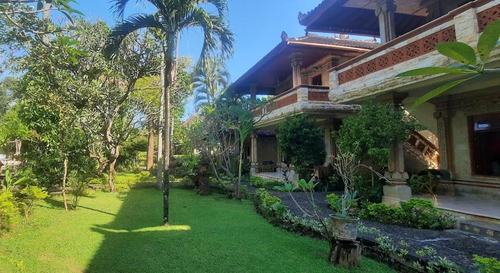 a house with a green yard in front of it at Rambutan Hotel in Lovina