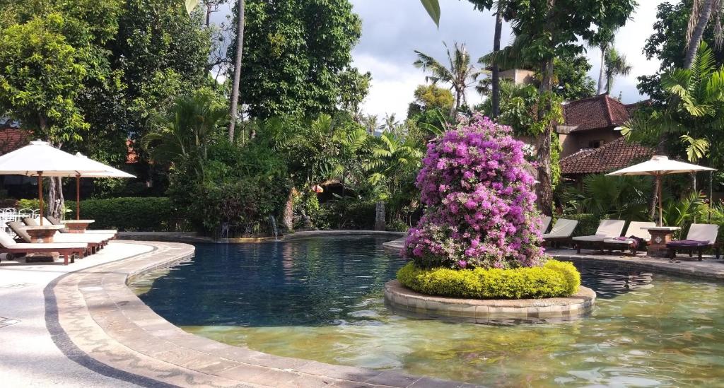 a pool with flowers in the middle of a resort at Rambutan Hotel in Lovina
