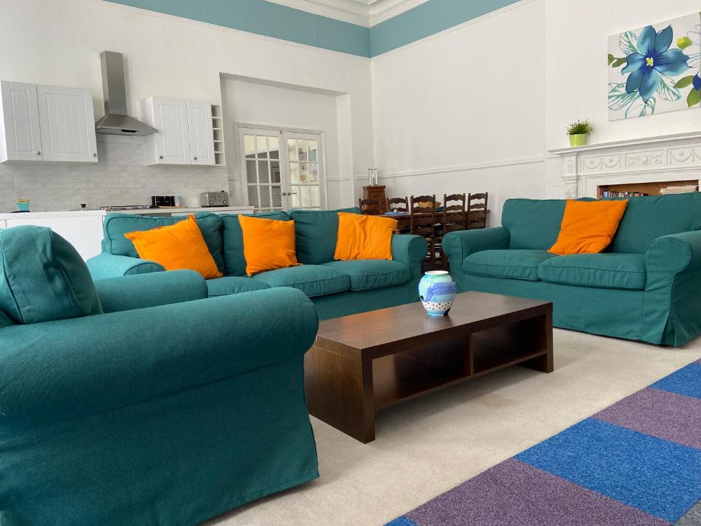 a living room with two blue couches and a coffee table at Gazeley Manor House - Central Huntingdon in Huntingdon