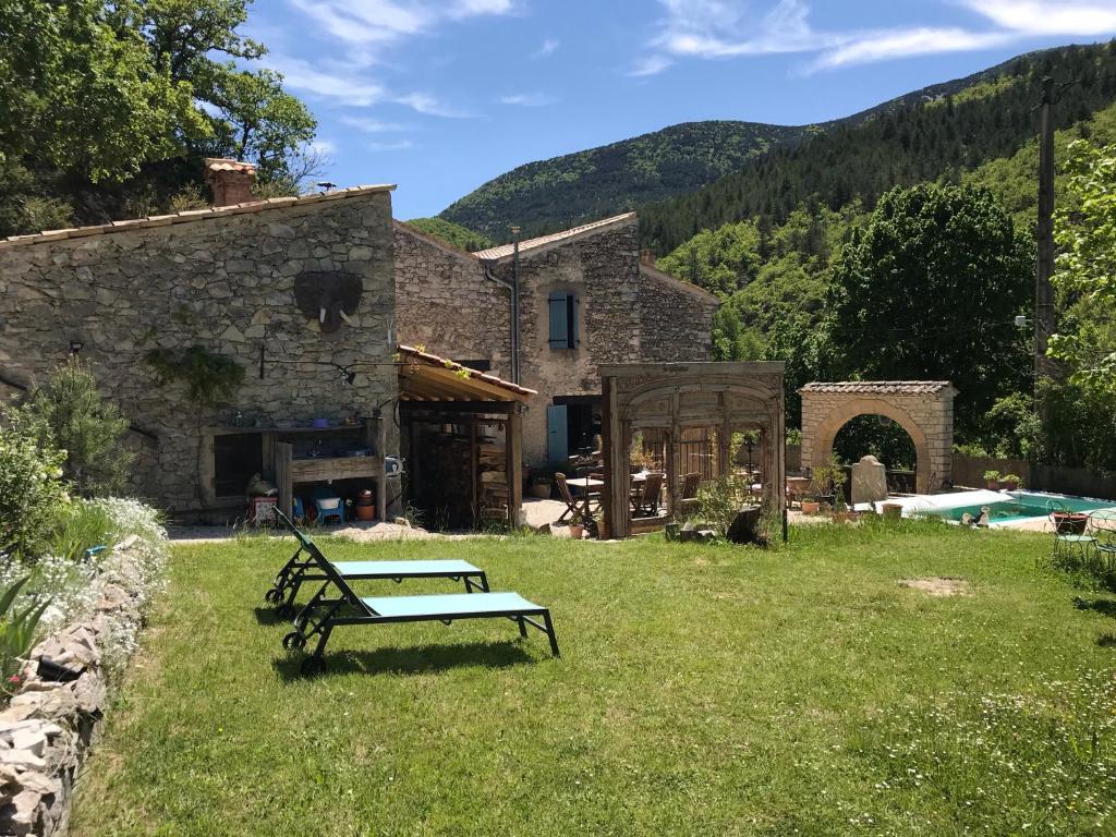 una casa de piedra con un banco en el patio en Mas de la Pauze, en Reilhanette
