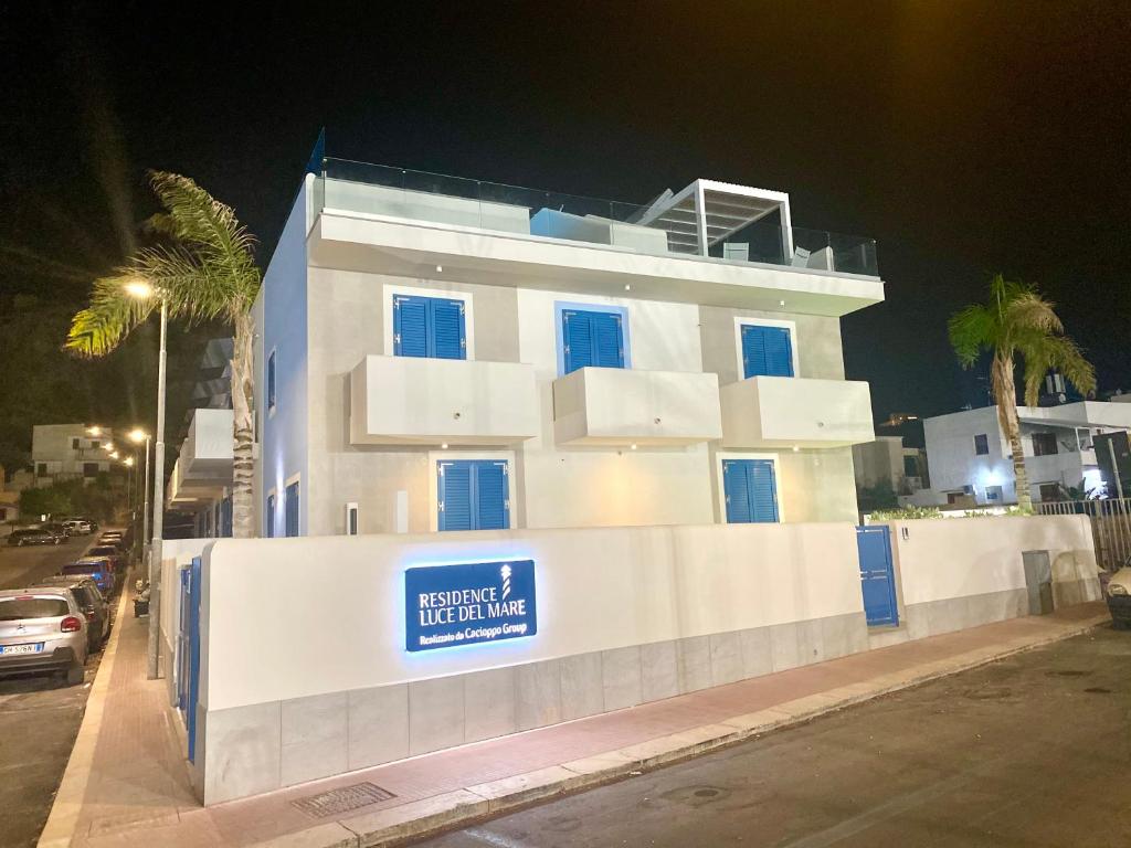 a white building with a blue sign on it at Zefiro&Levante2 Residence Luce del Mare in San Vito lo Capo