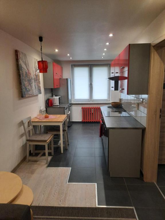 a kitchen with red cabinets and a table and chairs at Apartament Robotnicza in Sanok