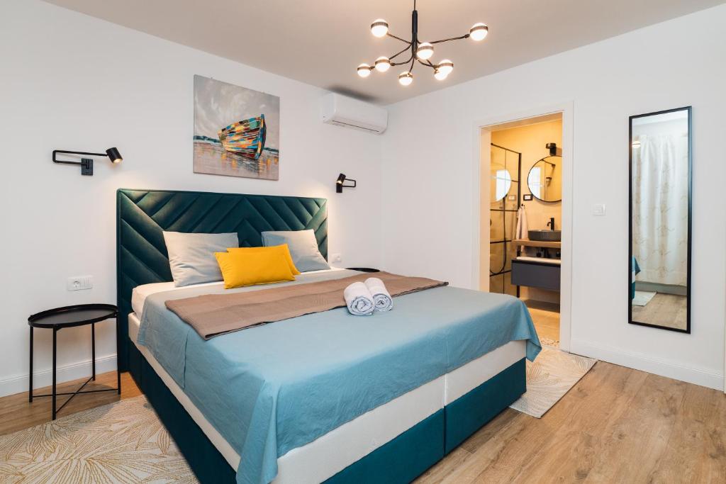 a bedroom with a large bed with a blue headboard at Amfora Maris Apartment in Split