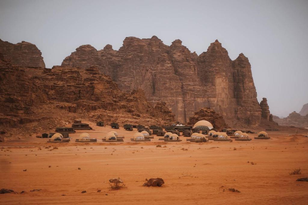 ein Gebäude inmitten einer Wüste mit einem Berg in der Unterkunft Sun City Camp in Wadi Rum