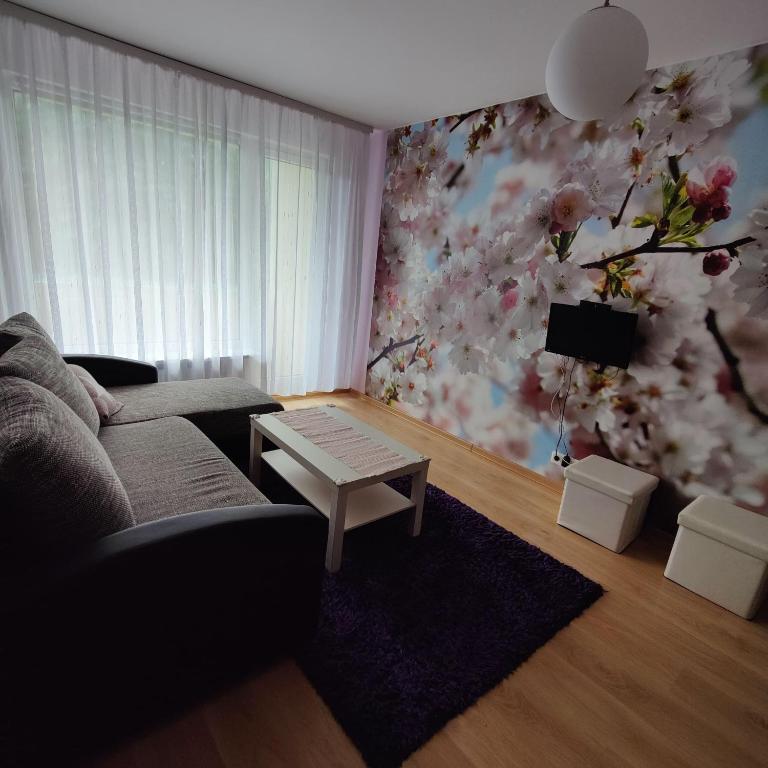 sala de estar con sofá y pared de flores en Dainai Apartament, en Šiauliai