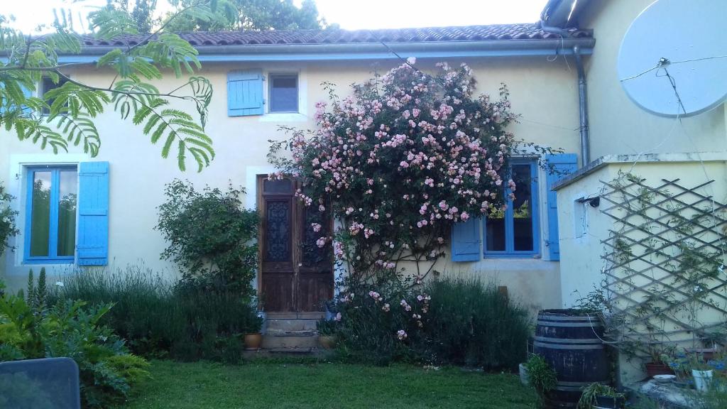 Biały dom z niebieskimi oknami i drzewem z różowymi kwiatami w obiekcie TheBees 