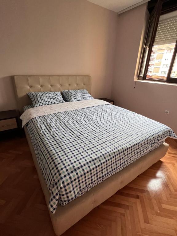 a bedroom with a large bed with a checkered blanket at Apartment 777 in Bijelo Polje