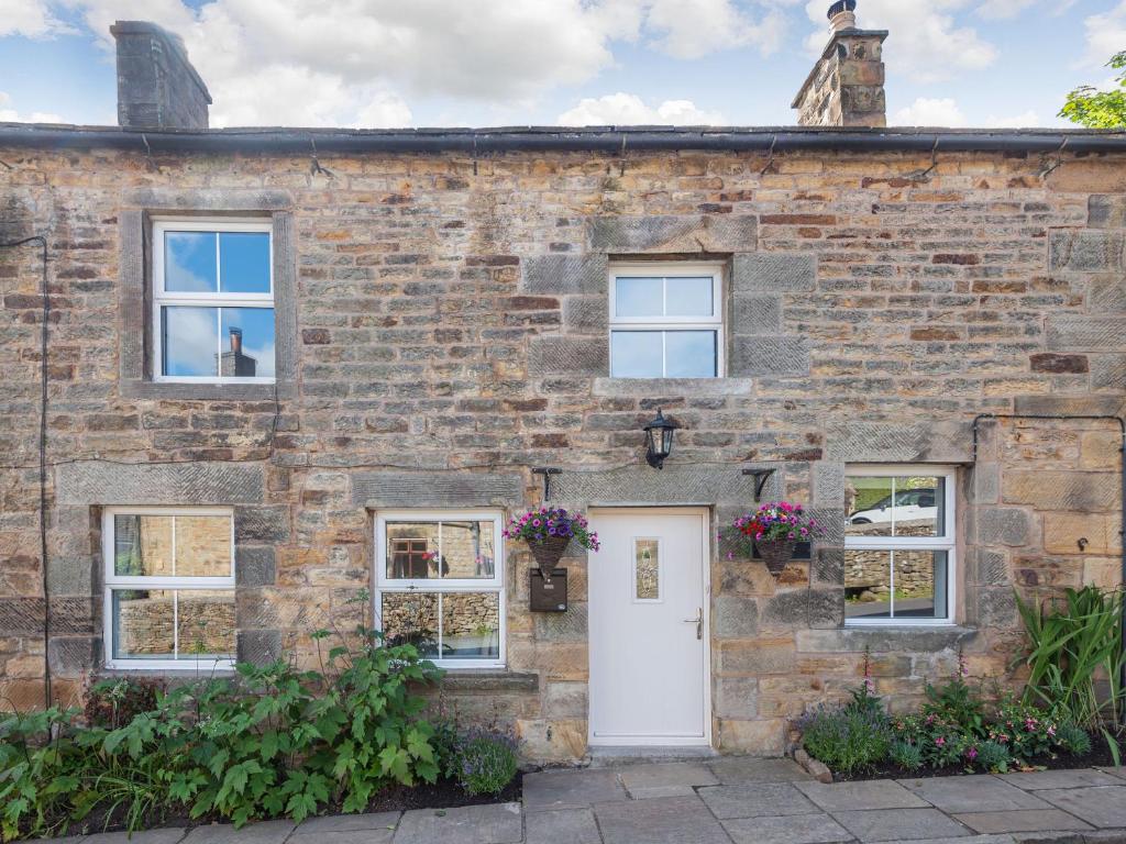 a brick house with a white door and windows at Carder Cottage in Longnor