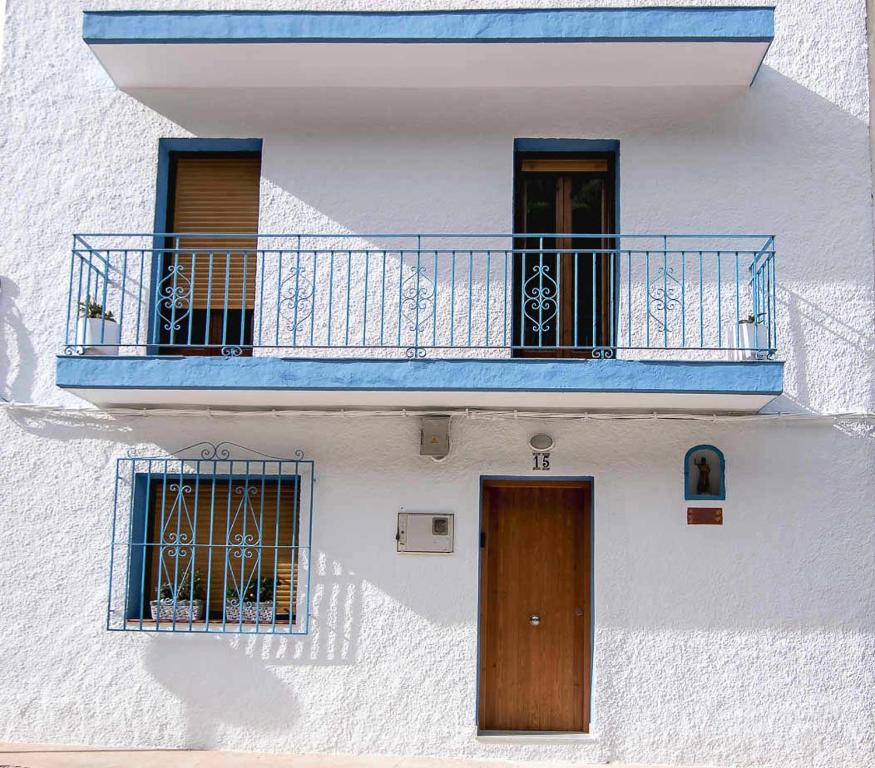 ein weißes Gebäude mit einem blauen Balkon und zwei Türen in der Unterkunft la Granadella paradis Home in Jávea