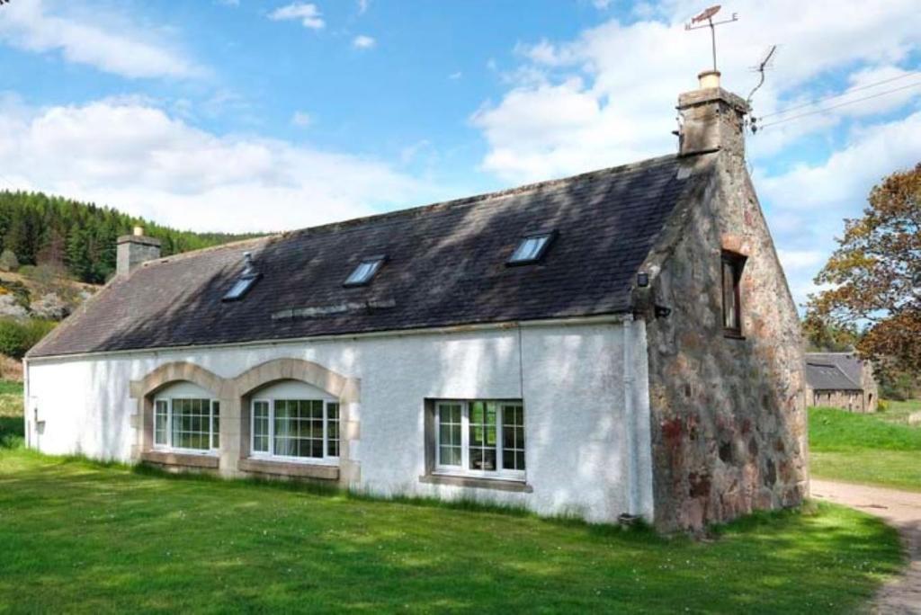 an old stone building on a grassy field at Garbity Cottage in Fochabers