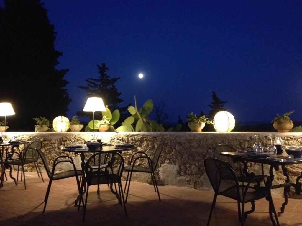 a row of tables and chairs on a patio at night at Hotel La Corte Del Sole in Noto