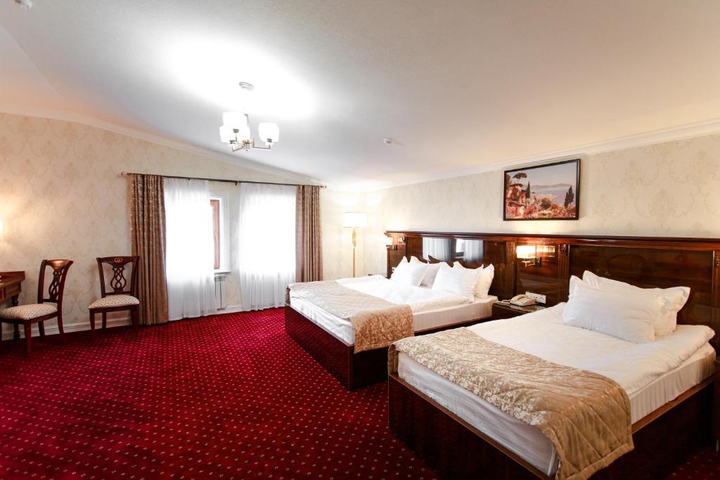 Cette chambre comprend 2 lits et un tapis rouge. dans l'établissement Konstantin Plaza, à Samarcande