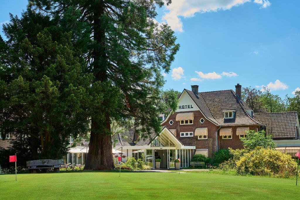 une grande maison avec un arbre dans la cour dans l'établissement Hotel 't Kruisselt, à De Lutte