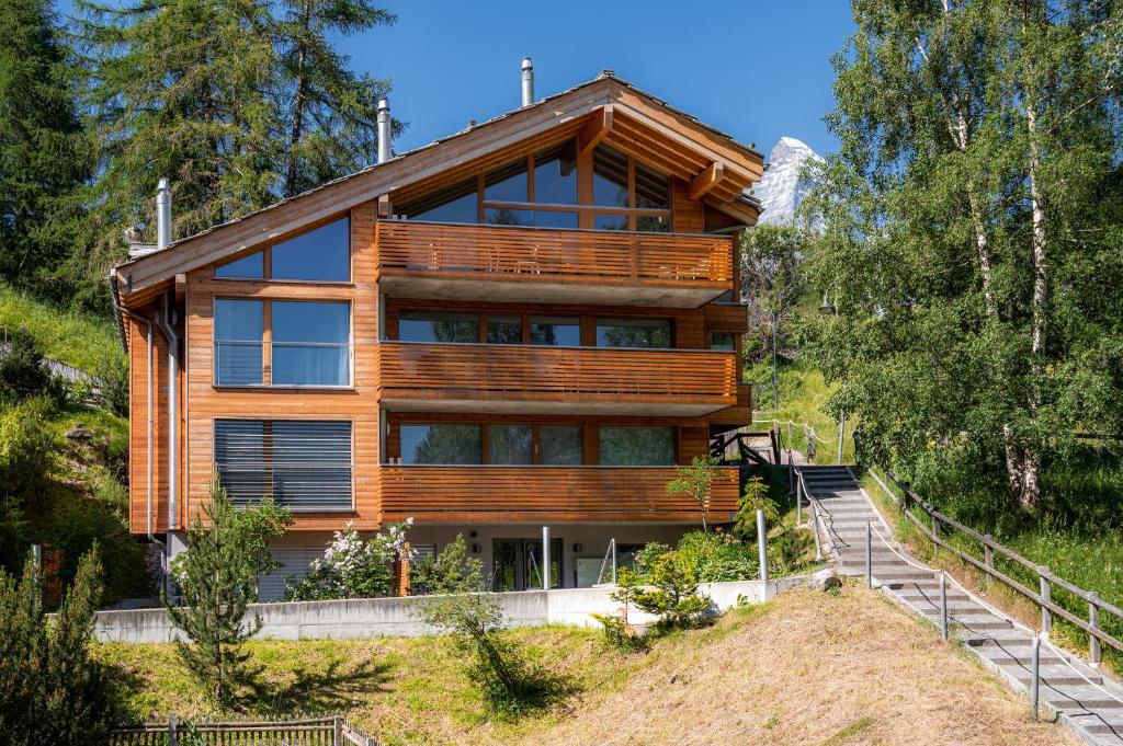 a house on top of a hill with trees at Luxury Chalets & Apartments by Mountain Exposure in Zermatt