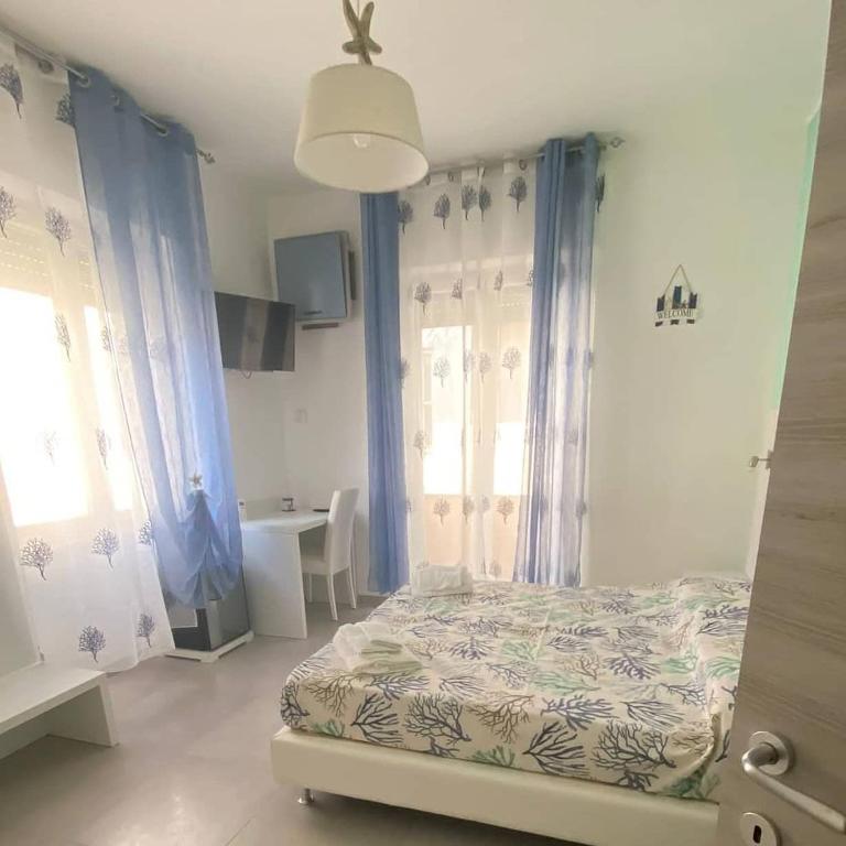 a bedroom with a bed with blue curtains and a window at Melody Rooms in Soverato Marina