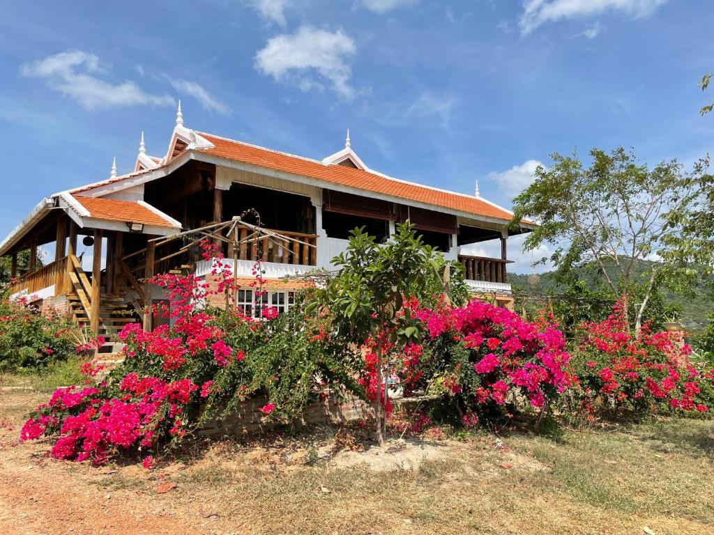 una casa con flores rosas delante de ella en Villa Secret Garden Kep-Panoramic view-WI-FI, en Phumĭ Prey Srâmaôch
