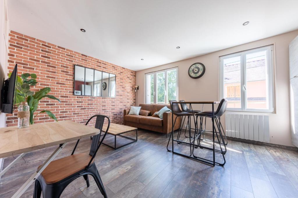 uma sala de estar com uma parede de tijolos e uma mesa e cadeiras em NOUVEAU - T2 Industriel - Quartier historique - WiFi - Parking - Netflix em Hennebont