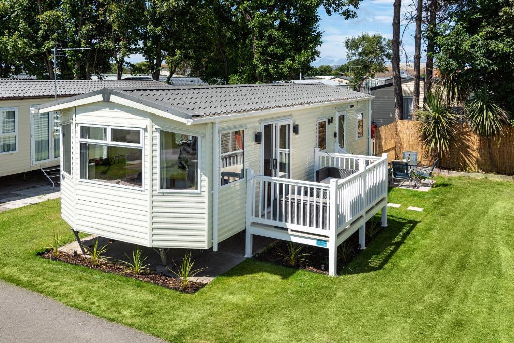 a white house with a porch on a yard at Dog Friendly Lovely Caravan by Beach Prestatyn N Wales 6 Berth Read full Host details before booking Mon in to Fri out Fri in to Mon out Mon to Mon Fri to Fri ONLY in Prestatyn