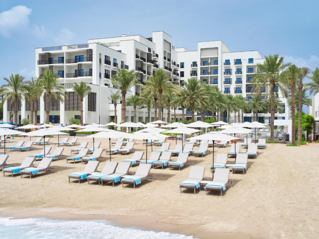 una fila de sillas de playa y sombrillas en una playa en Palace Beach Resort Fujairah, en Fujairah