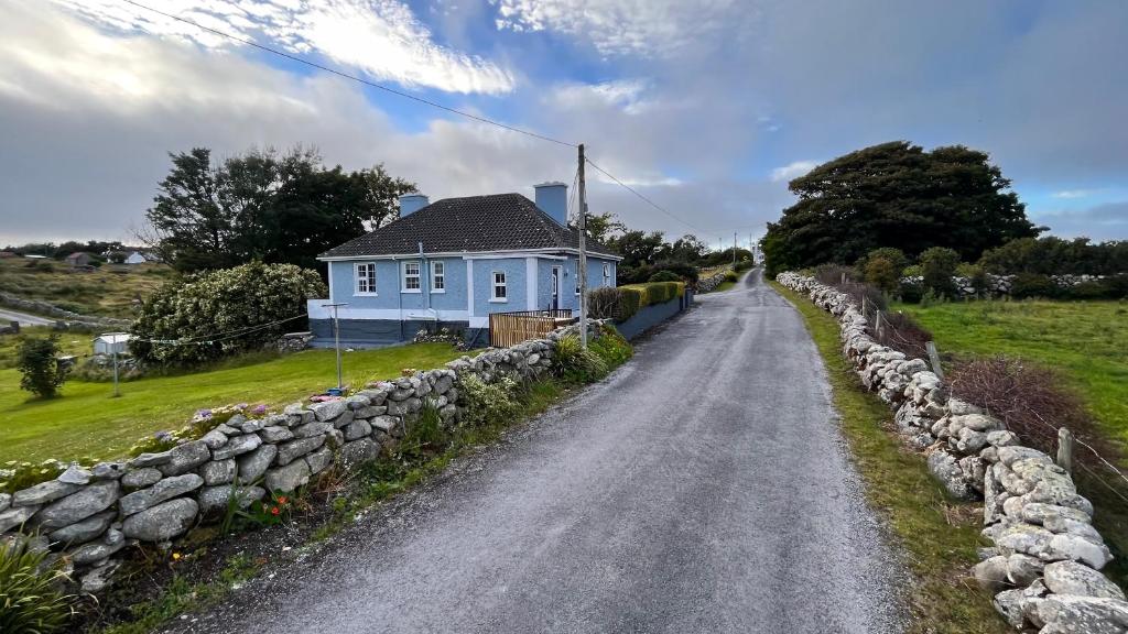 a house on a road next to a stone wall at Wild Atlantic Stay Cottage in Galway