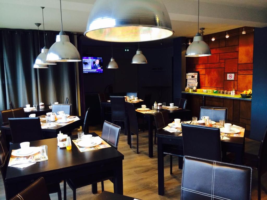 a dining room with tables and chairs and lights at Fasthotel Dunkerque in Grande-Synthe