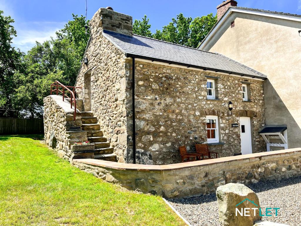 a stone house with a stone stairway leading up to it at Hafan Hedd Cottage in Solva