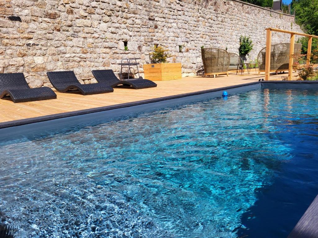 a swimming pool with lounge chairs next to a brick wall at LA MAISON 1788 in Meymac