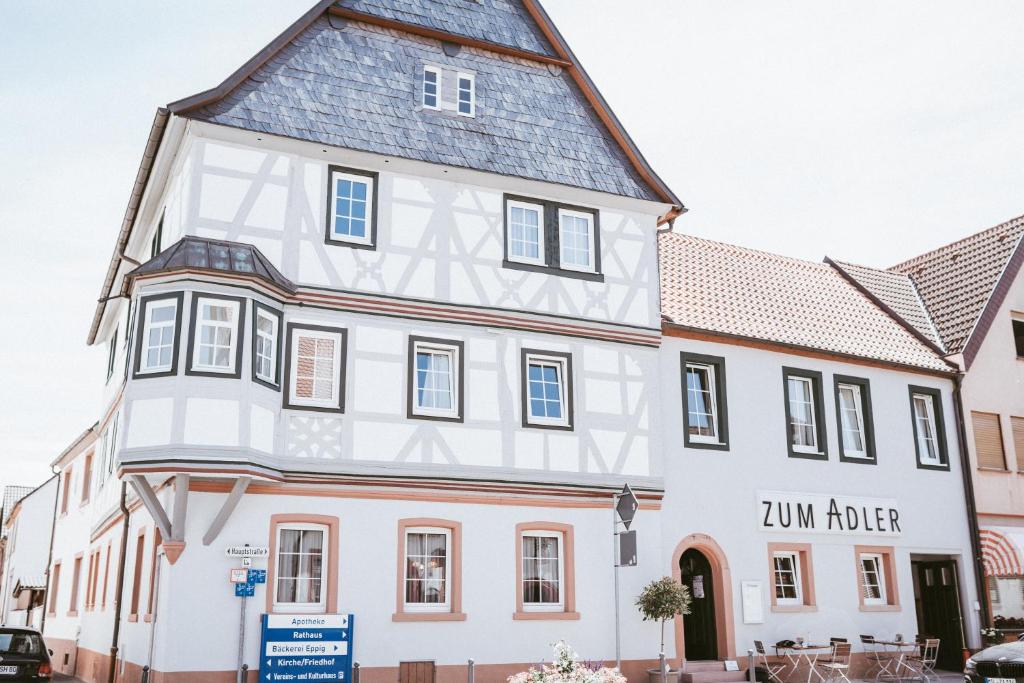 un grand bâtiment blanc avec un toit gris dans l'établissement Gasthaus Zum Adler, à Großwallstadt