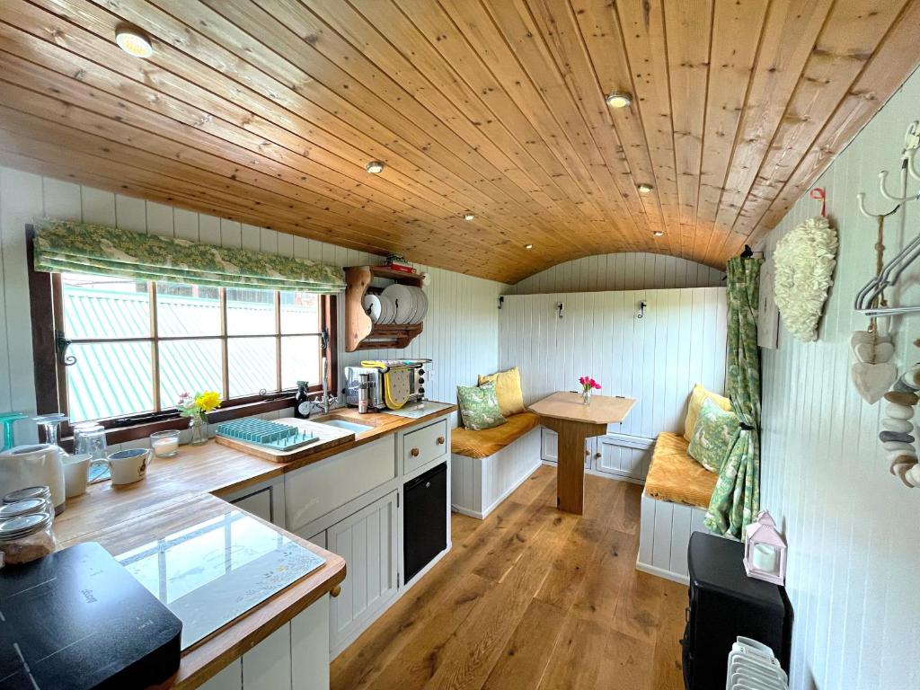 a kitchen with white cabinets and a wooden ceiling at Puddle Duck Shepherd Hut in Launceston
