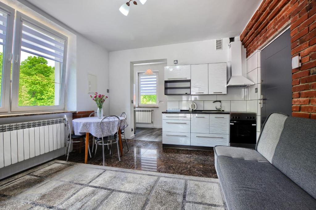 een keuken met witte kasten en een tafel met een eetkamer bij Ceglany Apartament in Ustrzyki Dolne