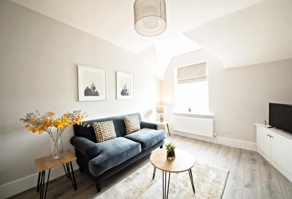 a living room with a blue couch and a tv at The Loft Apartment, 8 Granville Road in Harrogate