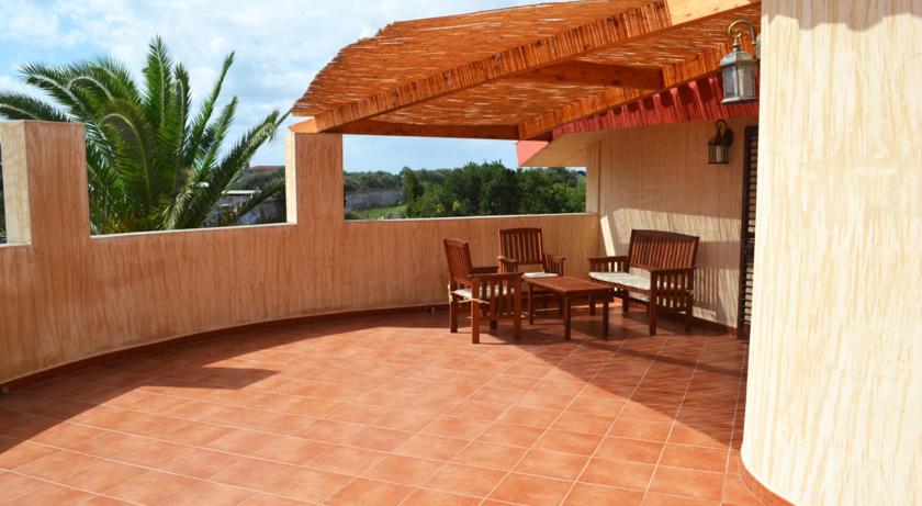 patio ze stołem, krzesłami i drewnianą pergolą w obiekcie Appartamenti famiglia Pinna - Villa Gioiosa - w mieście Cabras