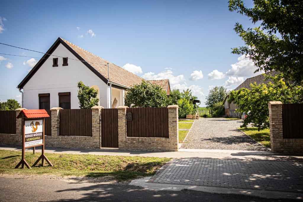 ein Haus mit einem Zaun und einem Schild davor in der Unterkunft Kergemókus Vendégház in Nagyberki