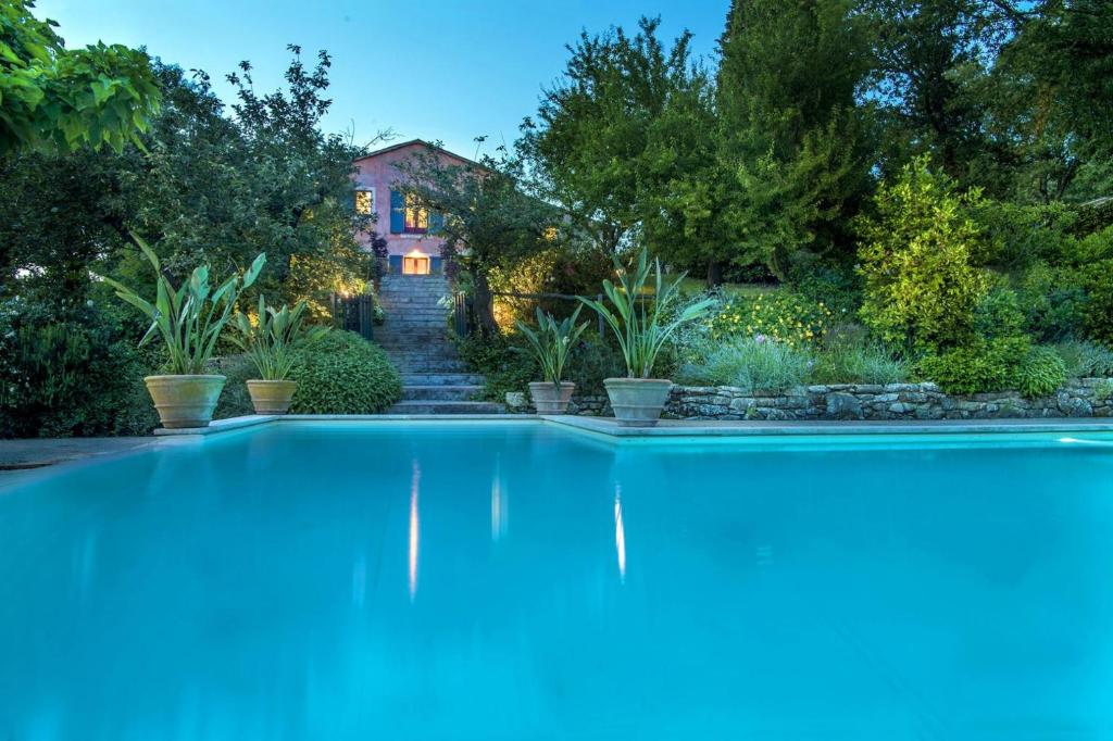 a swimming pool in a garden with a house in the background at Villa Patrizia 12 in San Casciano dei Bagni
