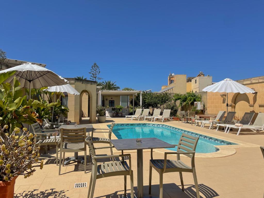 um pátio com uma mesa e cadeiras ao lado de uma piscina em IL-Gardjola Bed and Breakfast em Għarb