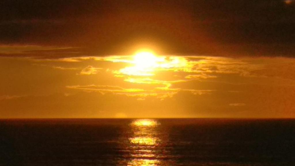 una puesta de sol sobre el océano con el sol en el cielo en El Ático Del Mar 5B, en Las Palmas de Gran Canaria