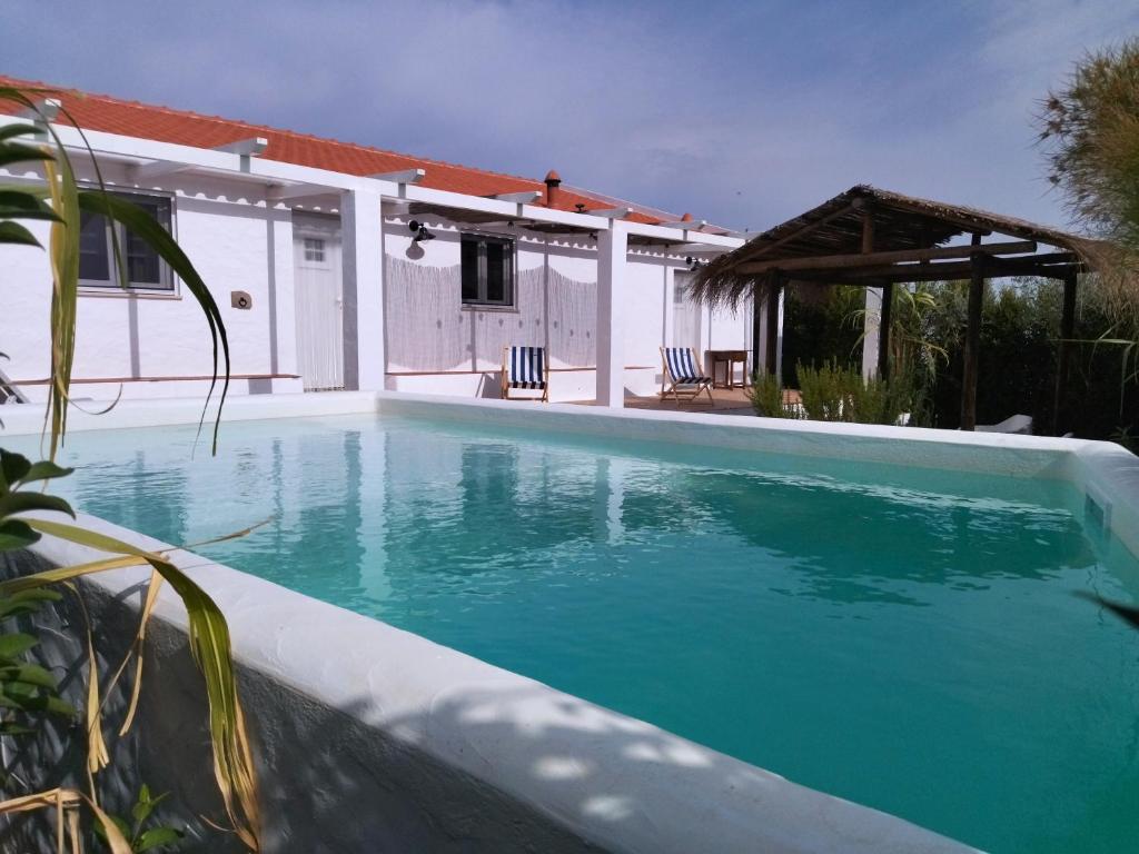 a swimming pool in front of a house at Monte da Rocha 3 Marias in São Bartolomeu da Serra