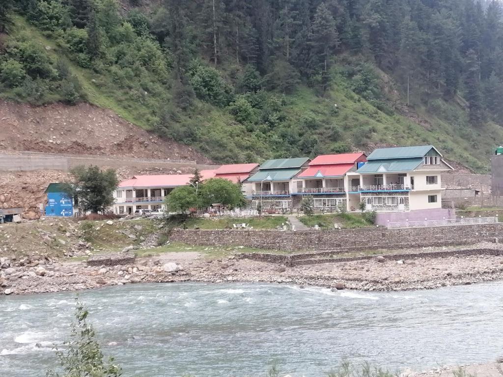 um grupo de casas ao lado de um rio em Parhena Cottages Bella Naran em Nārān