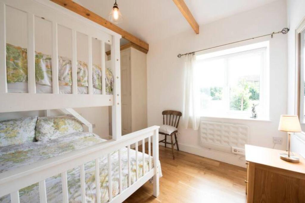 ein Schlafzimmer mit einem weißen Bett und einem Fenster in der Unterkunft Beautiful barn with private log fired hot tub in Maidstone