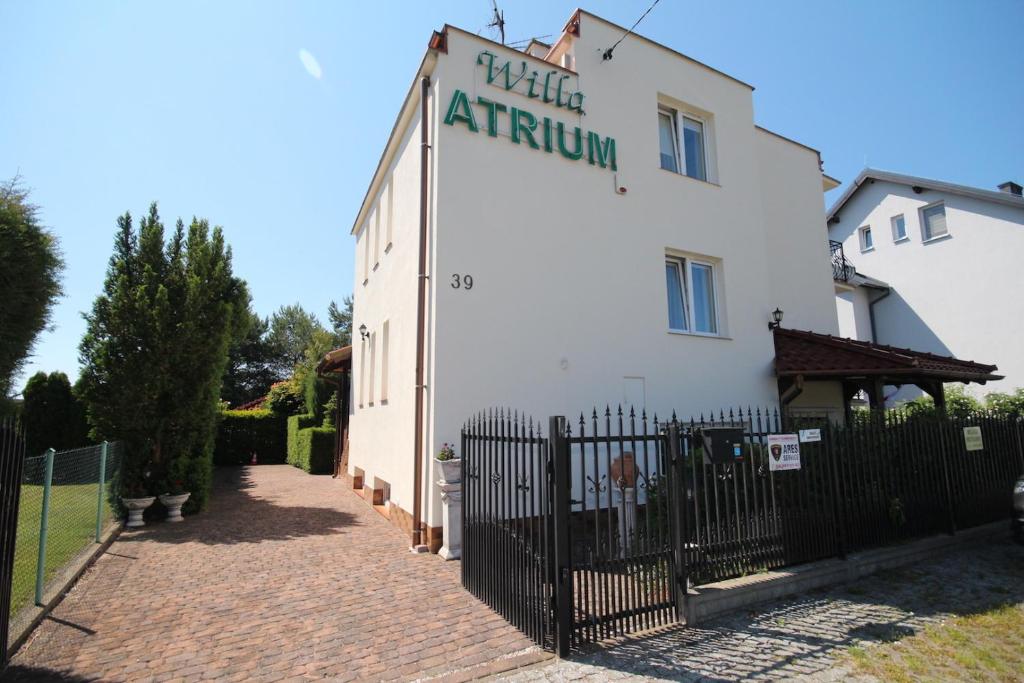 a white building with a fence in front of it at Willa Atrium in Jantar