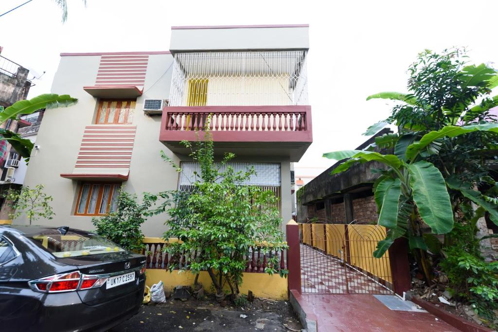 a house with a balcony and a car parked in front at Sterling Baishakhi in Kolkata