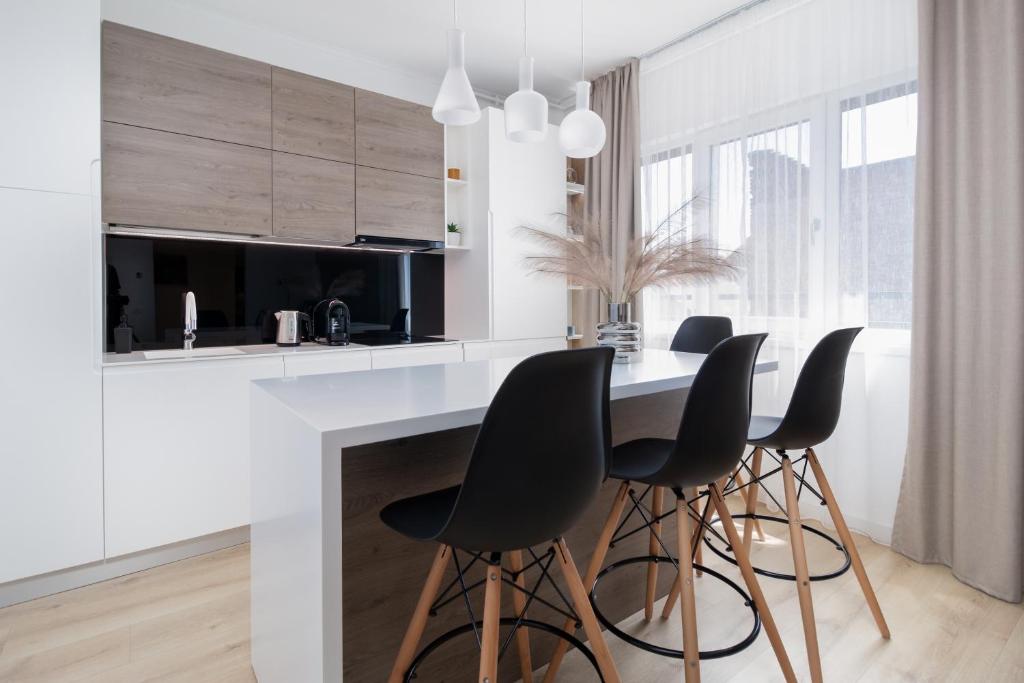 uma cozinha com cadeiras pretas e um balcão branco em Charlotte Piata Unirii - Free Parking 2bedrooms Apartment em Oradea