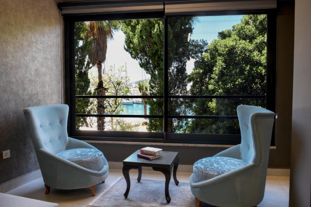 2 sillas y una mesa frente a una gran ventana en PIER21 house en Fethiye