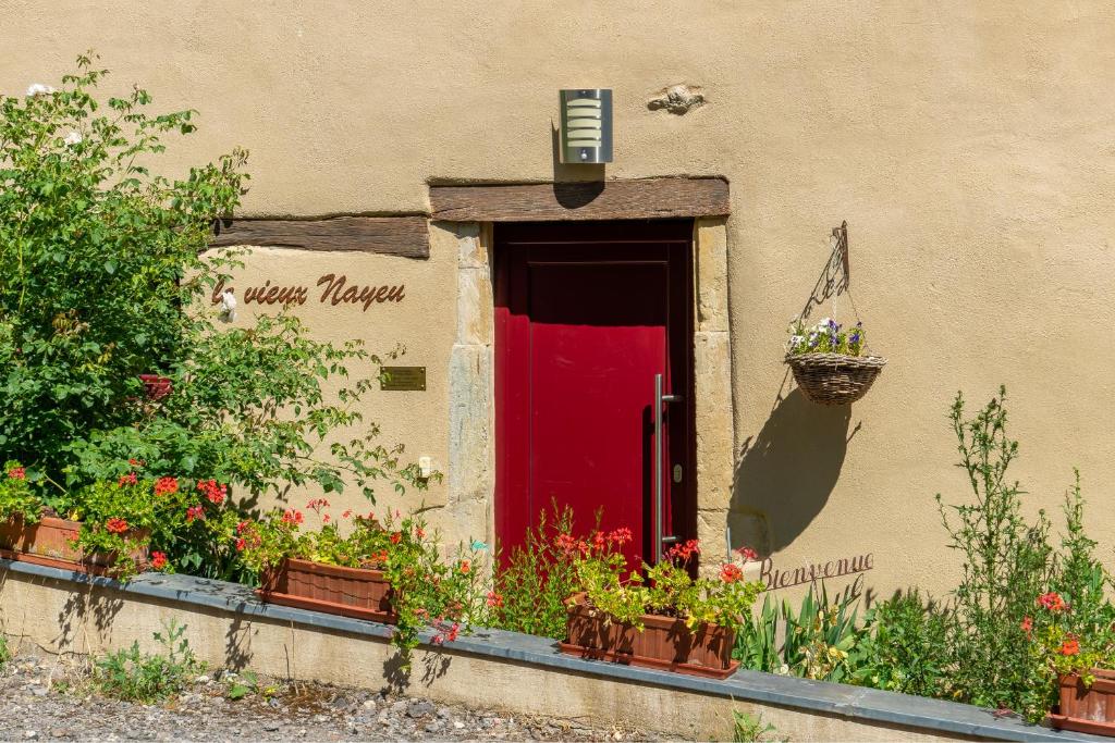 une porte rouge et quelques plantes et fleurs sur un bâtiment dans l'établissement LE VIEUX NAYEU, à Raville