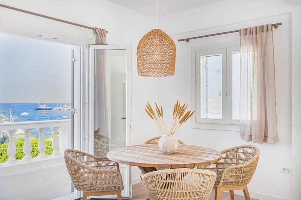 Pearl House - Luxurious new beach villa in Spetses stunning view في سبيتسيس: غرفة طعام مع طاولة وكراسي خشبية